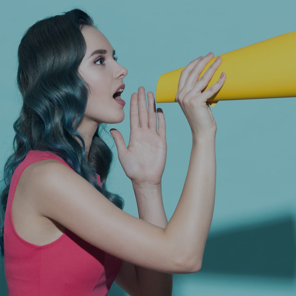 A young woman with long wavy hair, wearing a sleeveless pink dress, uses a yellow megaphone to speak. She is facing left against a teal background, with one hand beside her mouth in a speaking gesture.