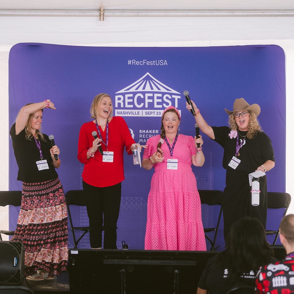 Four women on a stage with microphones in front of a branded RecFest USA backdrop.